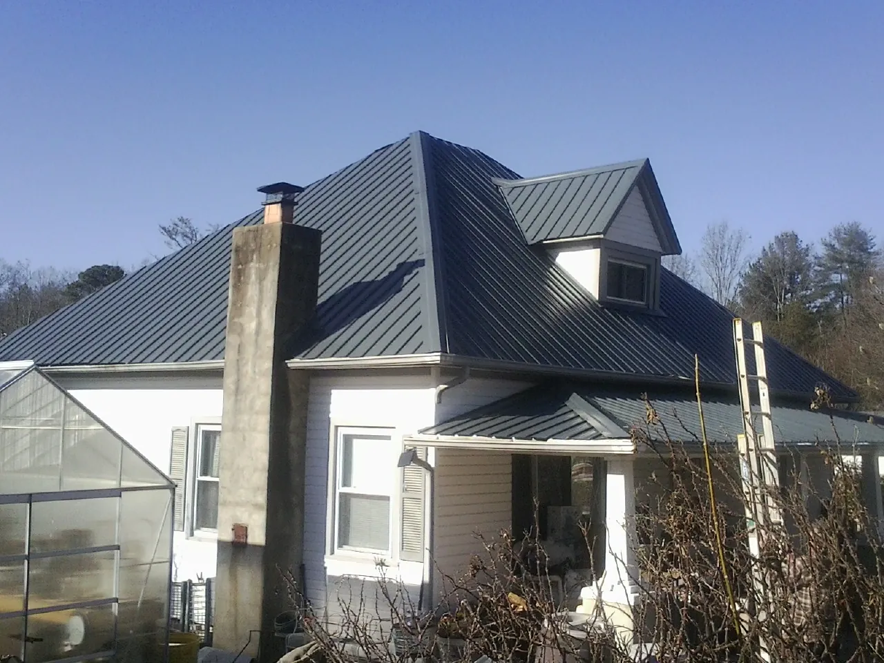 Dark blue standing seam metal roof on a white farmhouse with dormer — Slate & Tile Roof Repair by Roofing Brothers in Glade Spring