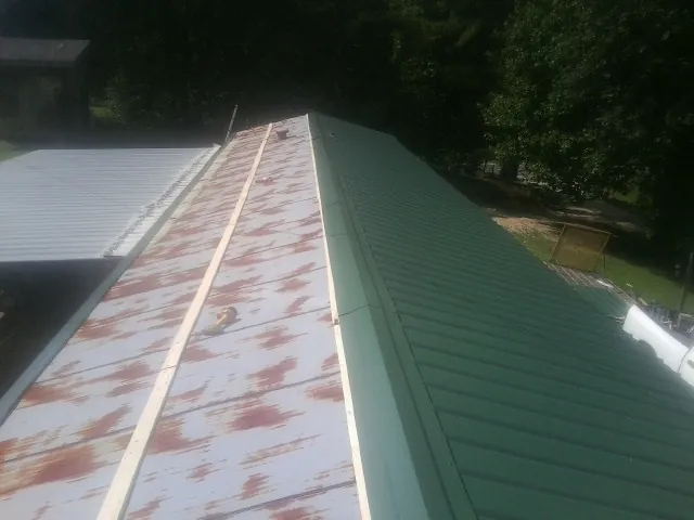 Old rusted panels beside newly installed green metal roofing — Wind Damage Roof Repair by Roofing Brothers in Glade Spring