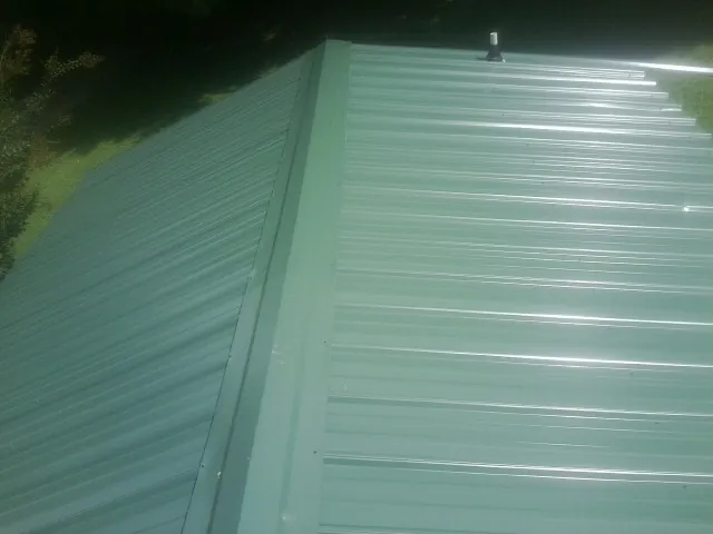 New green metal panels meeting at the ridge of a roof — Flat Roof Repair work by our crew in Glade Spring