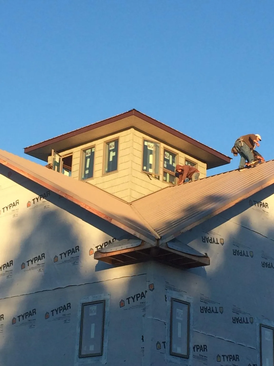 Roofers working around a rooftop cupola on a new metal roof at sunset — Roof Waterproofing in Glade Spring by Roofing Brothers